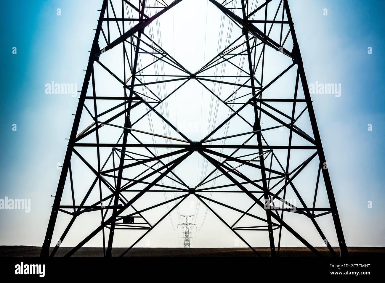 Le linee elettriche si estendono attraverso un cielo limpido con una vista dettagliata della struttura della torre in acciaio in primo piano, Auvergne Rhone Alpes, Francia Foto Stock