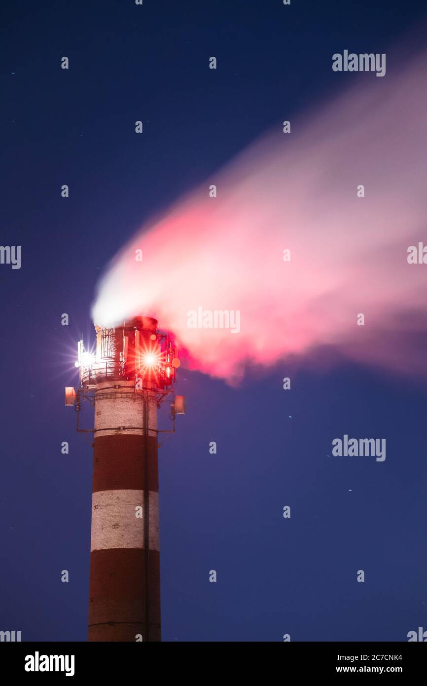 Torri cellulari per telecomunicazioni con antenne installate su Chimney di fabbrica. Pipe di pianta con vapore di fuga o fumo di notte Foto Stock