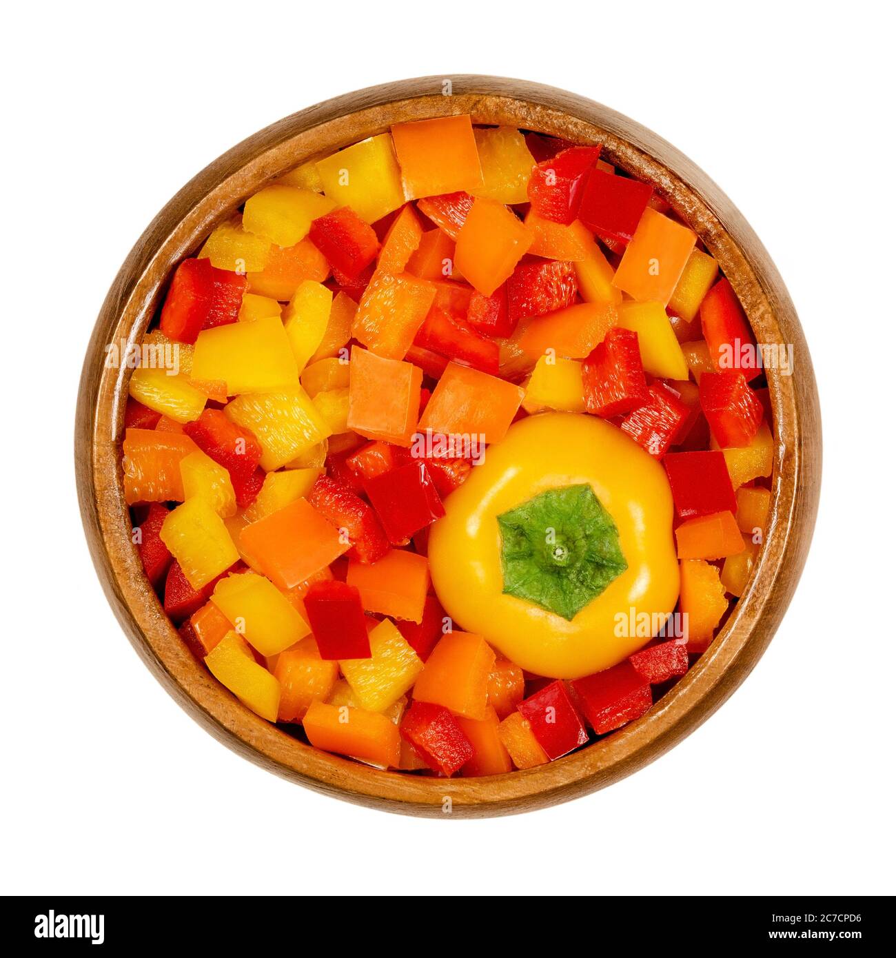 Testa di peperone e cialde a dadini in un recipiente di legno. Peperone dolce, capsicum, anche paprika, tagliato in patatine colorate. Frutta fresca gialla, arancione e rossa. Foto Stock