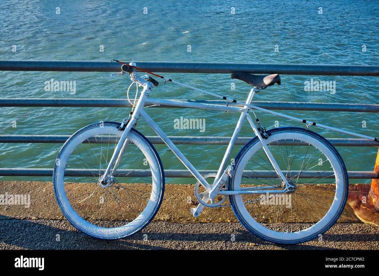 Ampio shot di una bicicletta da strada parcheggiata vicino all'acqua durante il giorno a Dunkerke, Francia Foto Stock