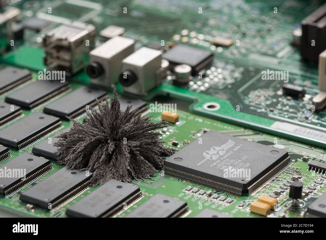 I campi magnetici che attraversano le schede PC per computer Mac, dove i filings in ferro mostrano linee di campo invisibili provenienti da un polo singolo di neodimio permanente Foto Stock