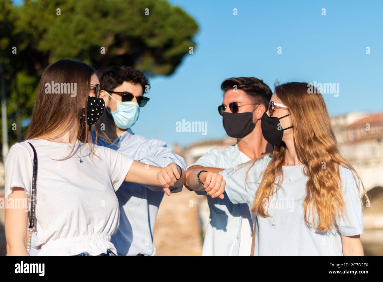 amici bramatori con gomiti - quattro giovani dicono ciao al tempo del coronavirus Foto Stock