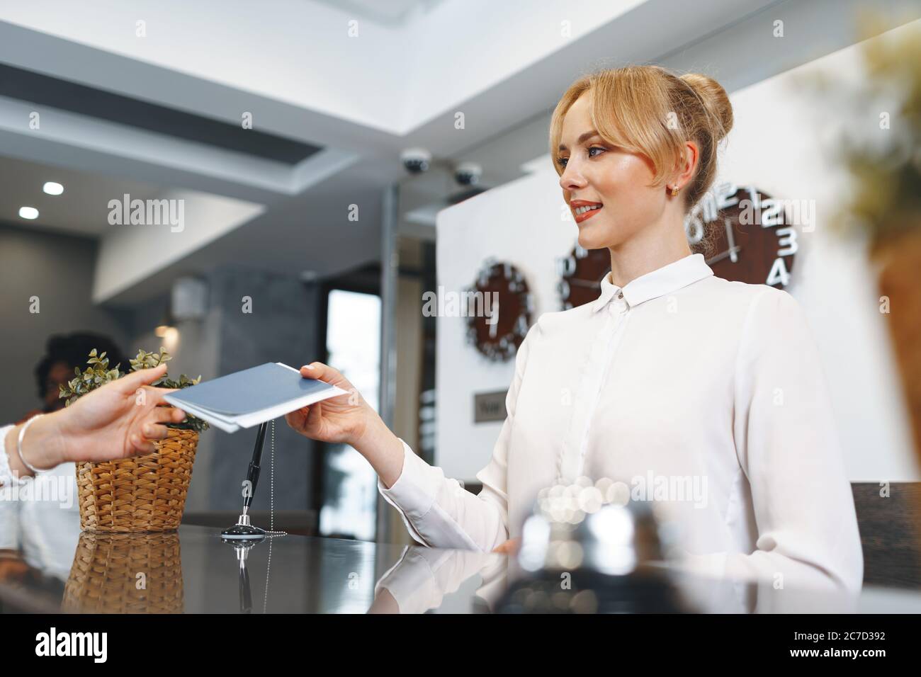 La donna della reception dell'hotel porta il passaporto dell'ospite per il check in Foto Stock