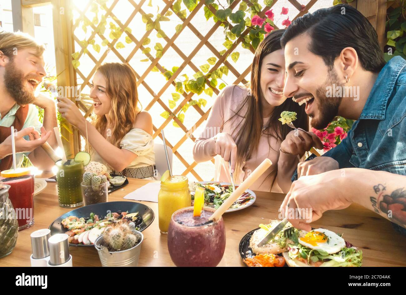 Amici felici che pranzano con cibo sano nel brunch del caffè del bar - i giovani che mangiano e bevono frullati frutta fresca nel ristorante Foto Stock