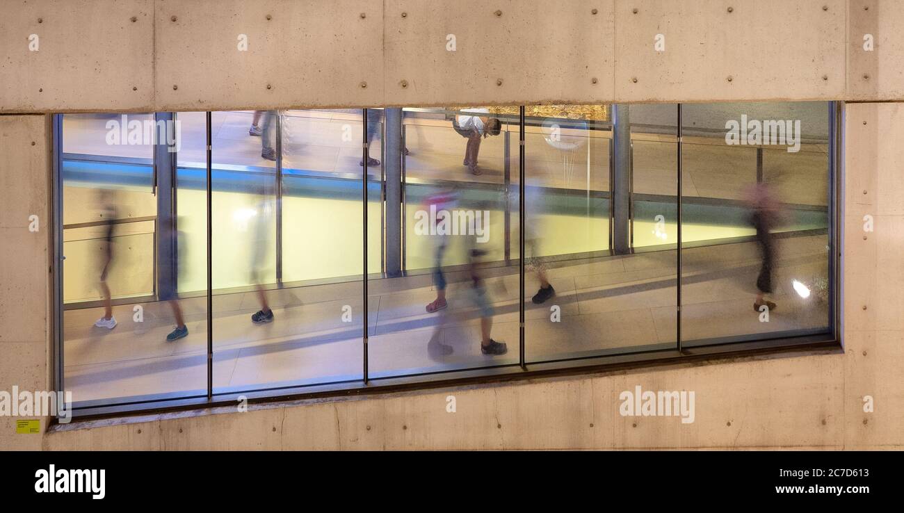 Immagine orizzontale di una finestra su una parete marrone e. il riflesso di persone che camminano nella sala Foto Stock