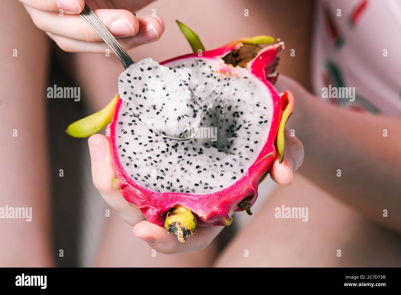 La ragazza sta mangiando una frutta tropicale con un cucchiaio. Dolce e fresco nutrito. Dragon Fruit primo piano. Foto Stock