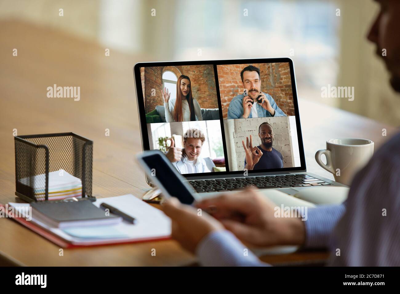 Riunione remota. Uomo che lavora da casa durante la quarantena di coronavirus o COVID-19, concetto di ufficio remoto. Giovane uomo d'affari, manager davanti al monitor durante una conferenza online con colleghi e team. Foto Stock