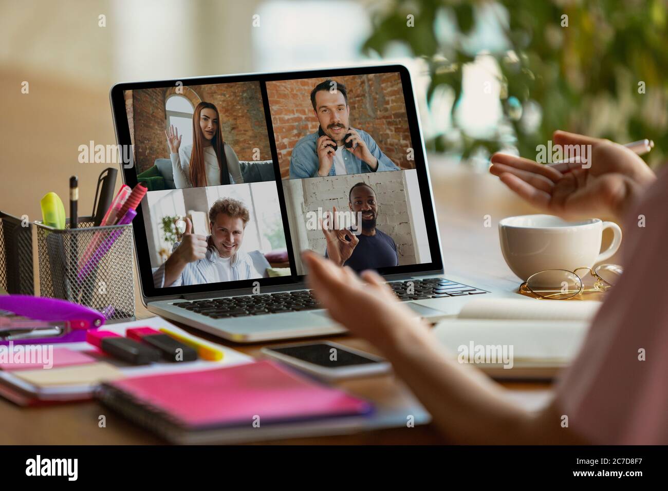 Riunione remota. Donna che lavora da casa durante il coronavirus o COVID-19 quarantena, concetto di ufficio remoto. Giovane capo, manager davanti al monitor durante una conferenza online con colleghi e team. Foto Stock