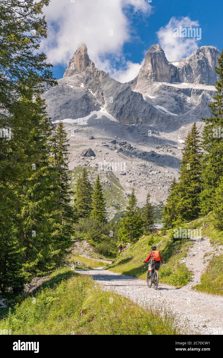 donna anziana che guida la sua mountain bike elettrica fino al Lindau Hut sotto le famose cime di Drusenfluh e tre Torri nella zona di Montafon di Vo Foto Stock