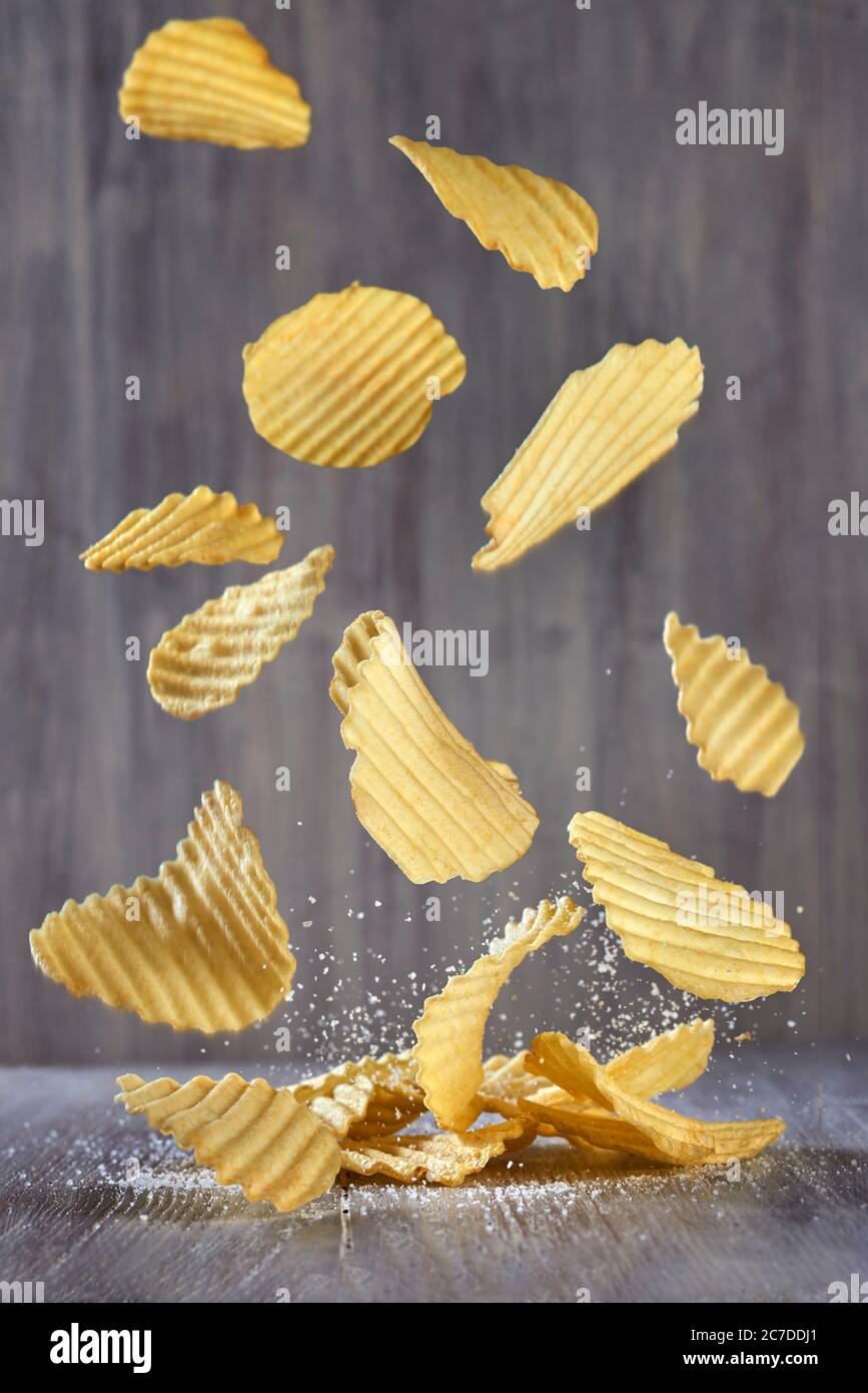 Un mucchio di patatine croccanti e salate cade sul tavolo. Cibo spazzatura, malsano, salato. Foto Stock