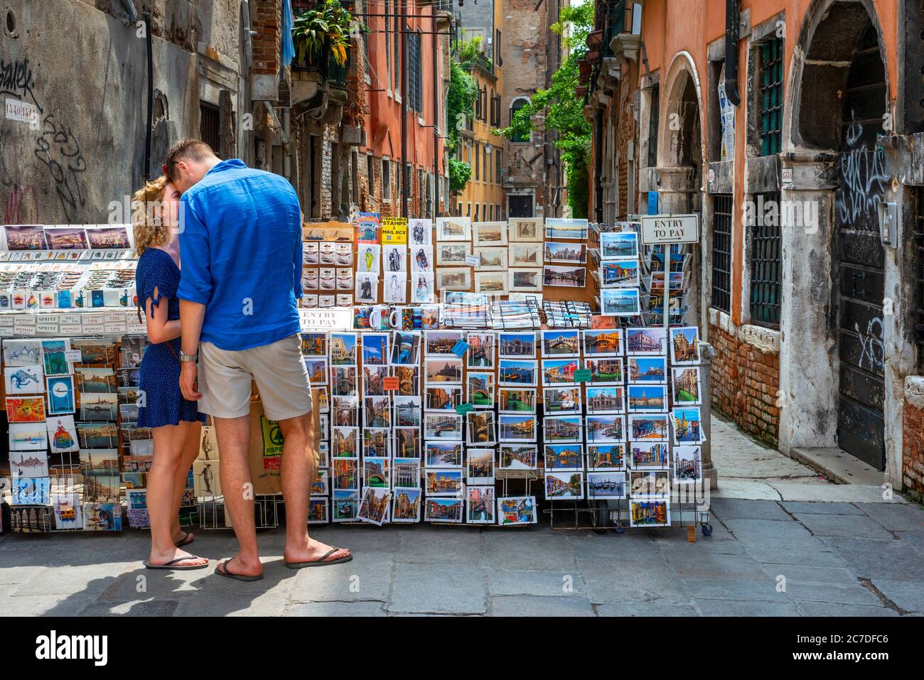Una coppia romantica esprime il proprio amore baciandosi nel centro di Venezia vicino a un negozio di cartoline. Venezia, Italia. Coppia Romainica baciando a Canal's. Foto Stock
