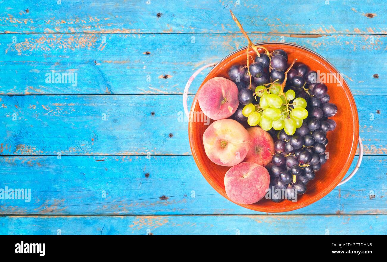 uva da vino e pesche, piatto su un tavolo rustico, buono spazio copia Foto Stock