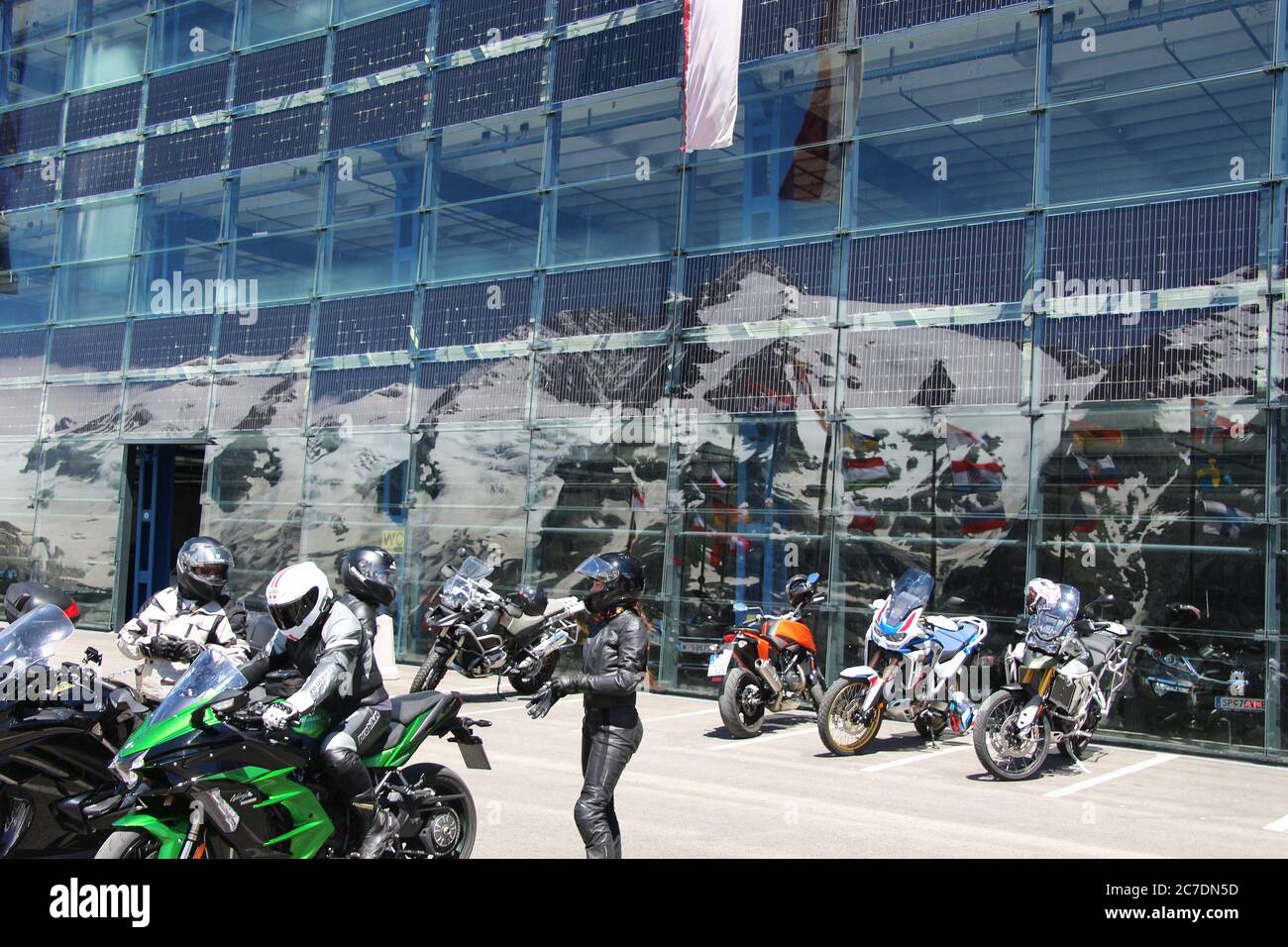 Franz-Josefs-Höhe, Austria: Motociclisti sulla famosa terrazza panoramica (altezza 2369 m) di fronte alla facciata in vetro del parcheggio. Europa. Foto Stock