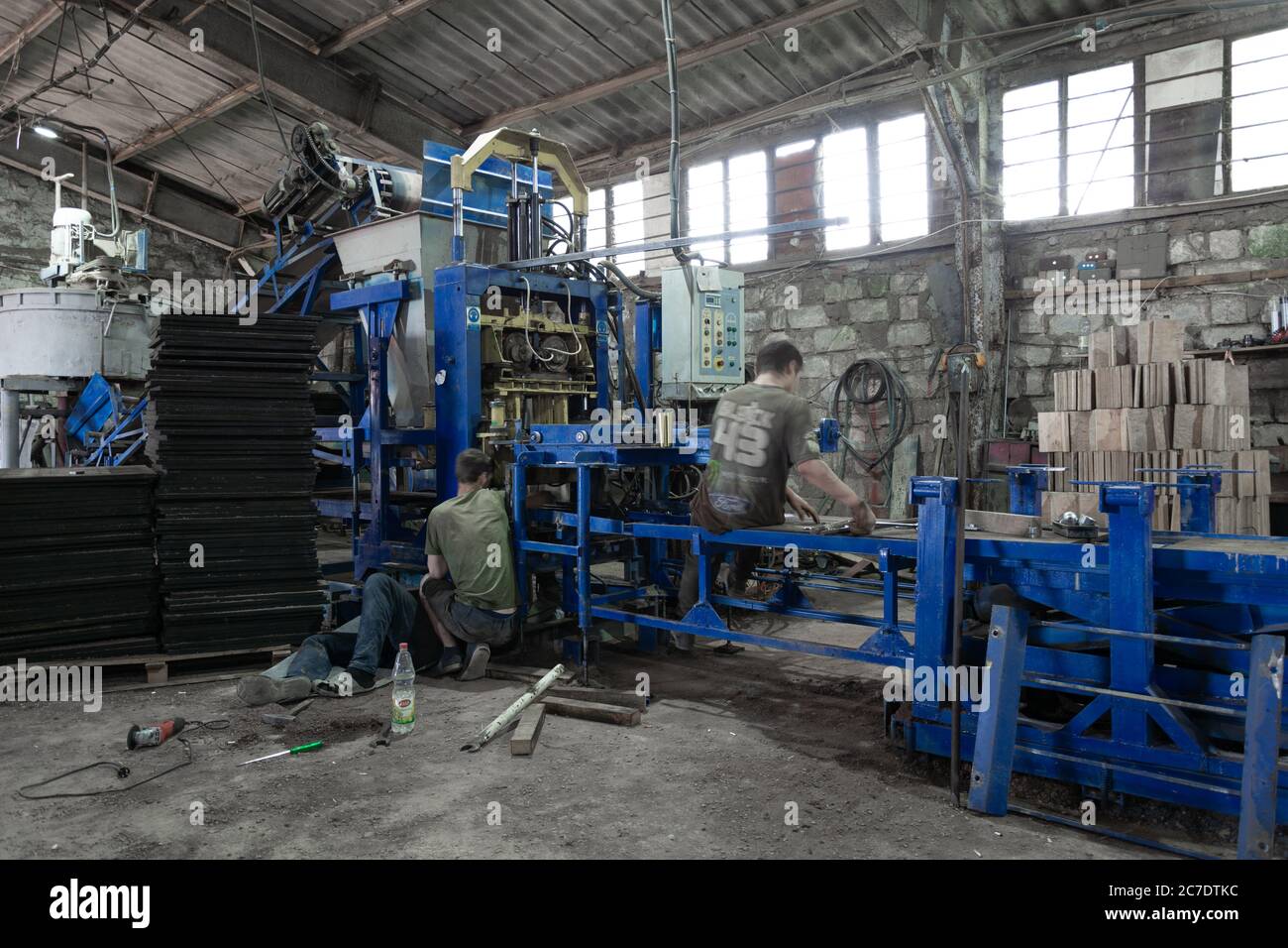 Moldavia, Bender - 28 giugno 2019: I lavoratori riparano il trasportatore per la produzione di lastre per pavimentazione. Foto Stock