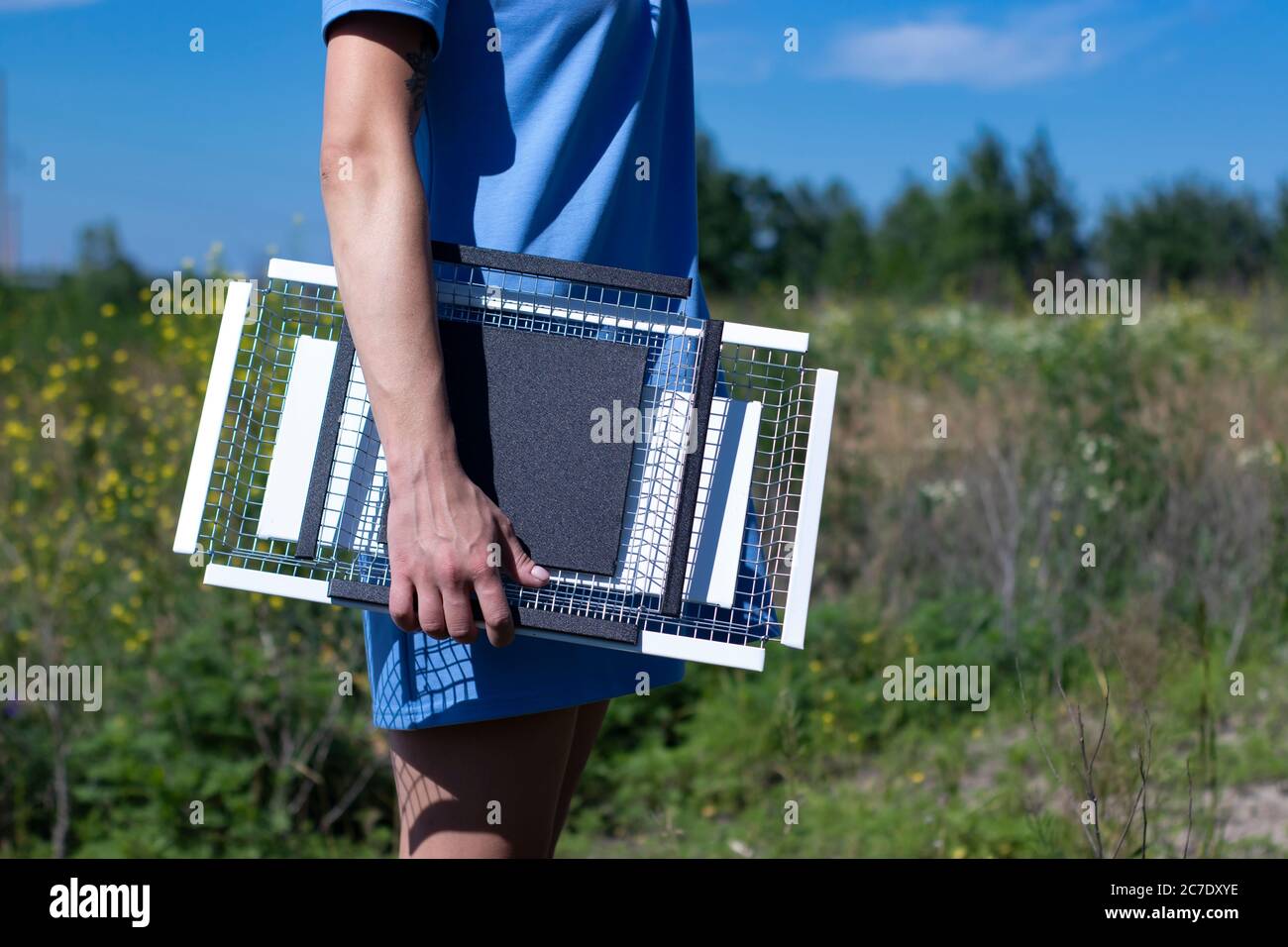 ragazza sottile in un abito blu tiene due vassoi di metallo bianco e nero fatti a mano nel campo. Niente volto, interni e decorazioni. Foto di alta qualità Foto Stock