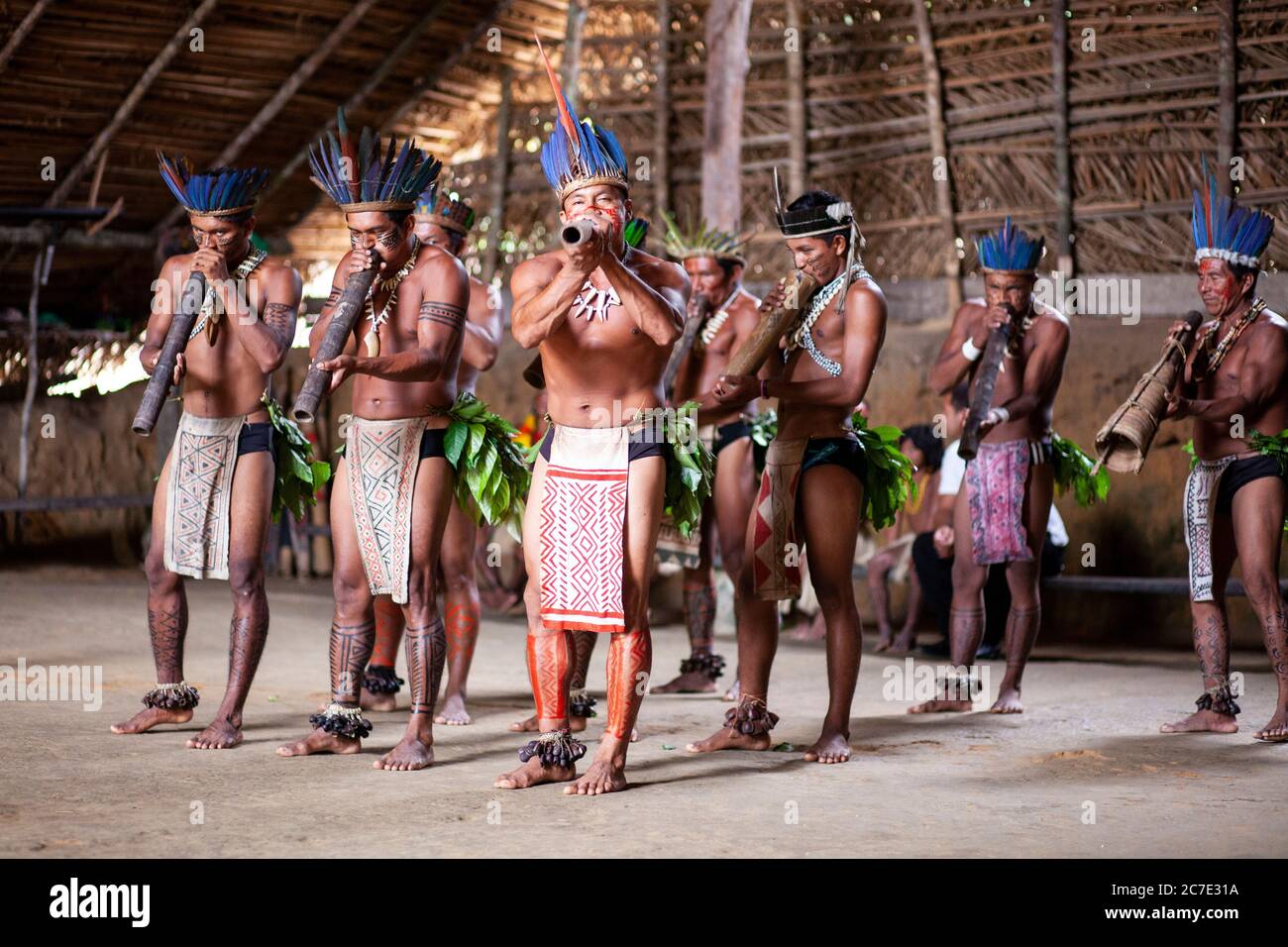 Uomini indigeni che soffiano su uno strumento tradizionale Foto Stock