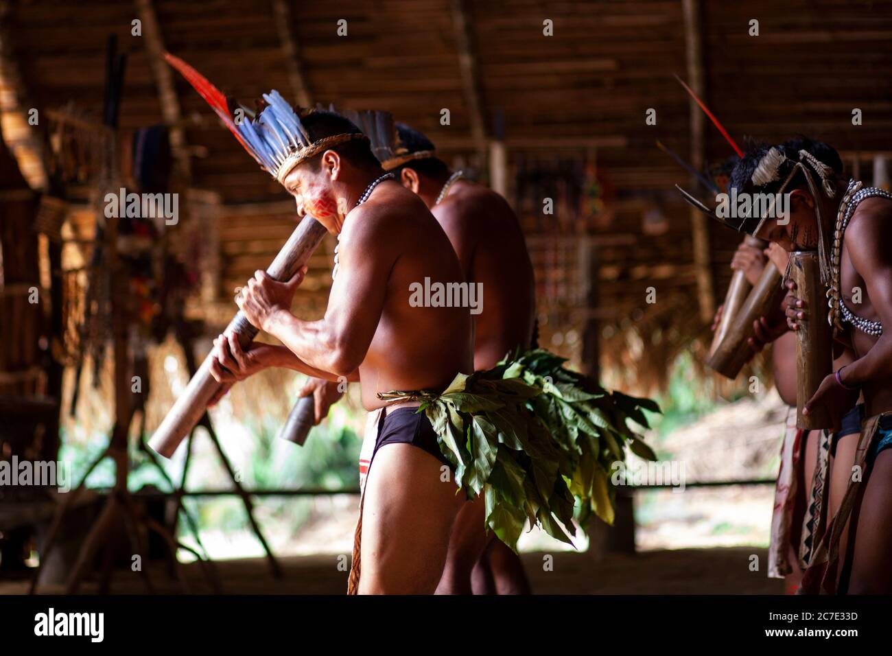 Uomini indigeni che soffiano su uno strumento tradizionale Foto Stock