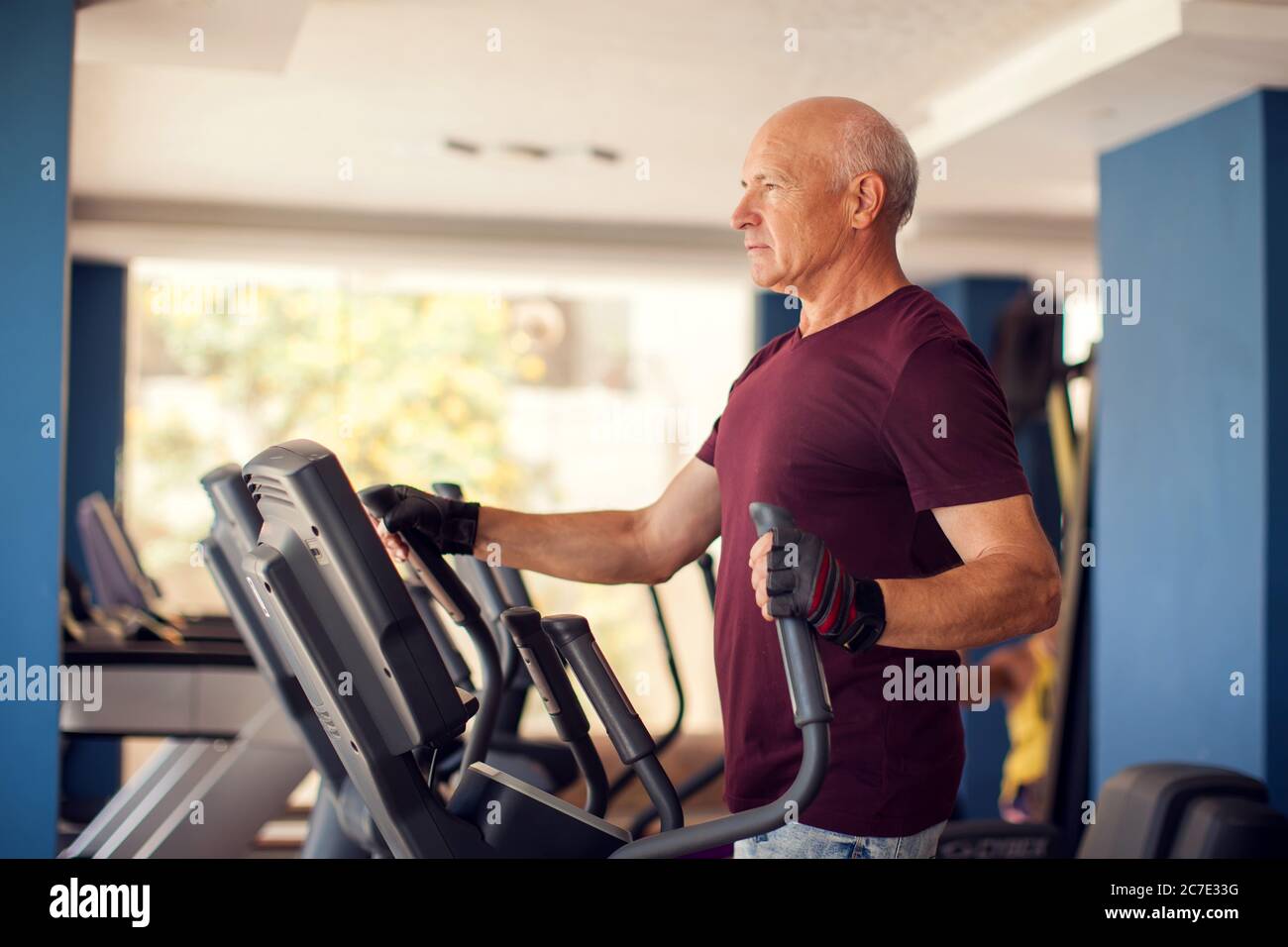 Un ritratto di calvo anziano nella palestra di allenamento nella zona cardio. Concetto di persone, salute e stile di vita Foto Stock