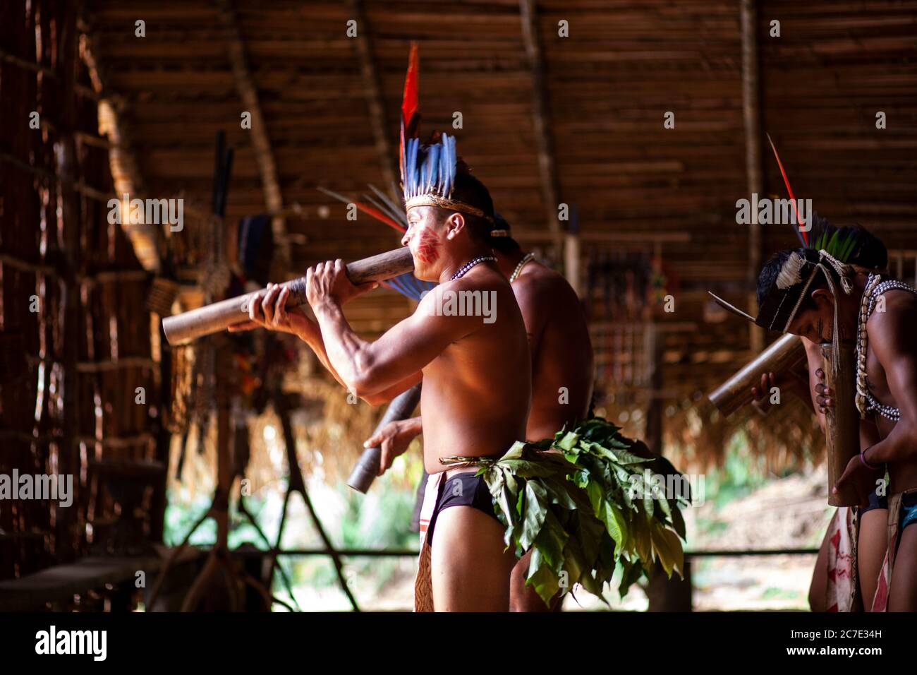 Uomini indigeni che soffiano su uno strumento tradizionale Foto Stock