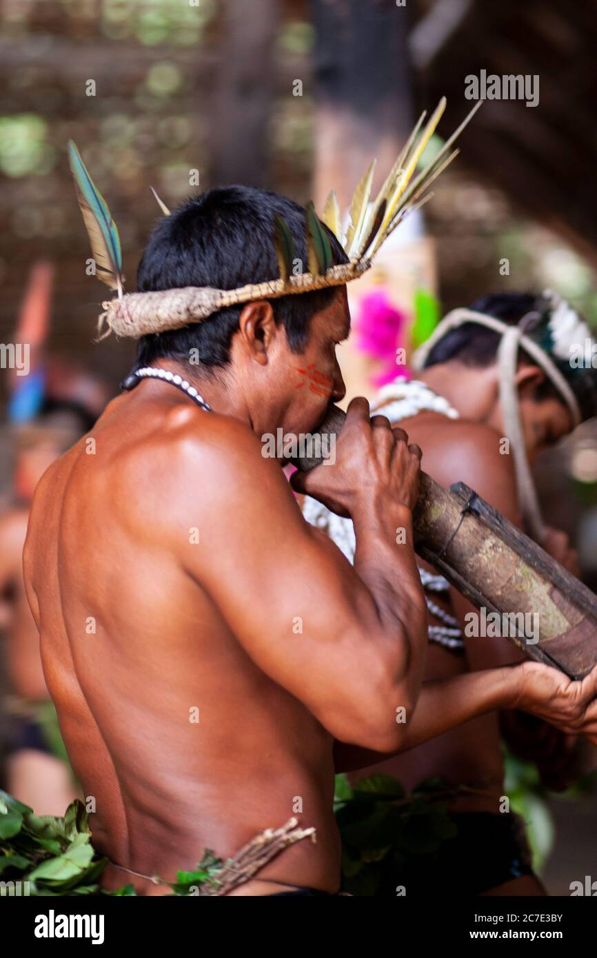 Uomini indigeni che soffiano su uno strumento tradizionale Foto Stock