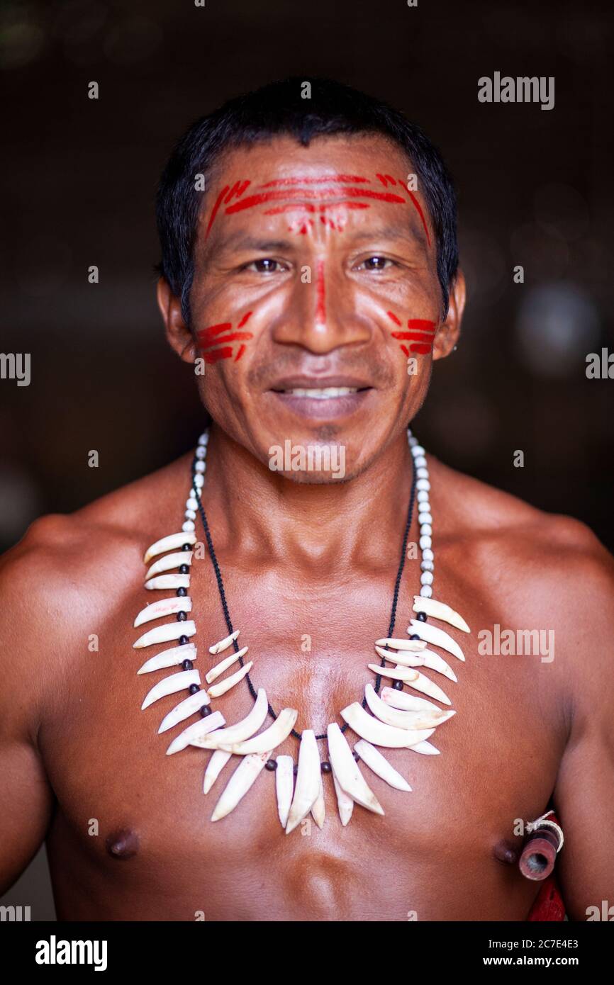 Ritratto di un uomo indigeno amazzonico con tradizionale vernice per il viso e una collana di denti tribali, che riflette il patrimonio culturale della cultura nativa del Brasile Foto Stock
