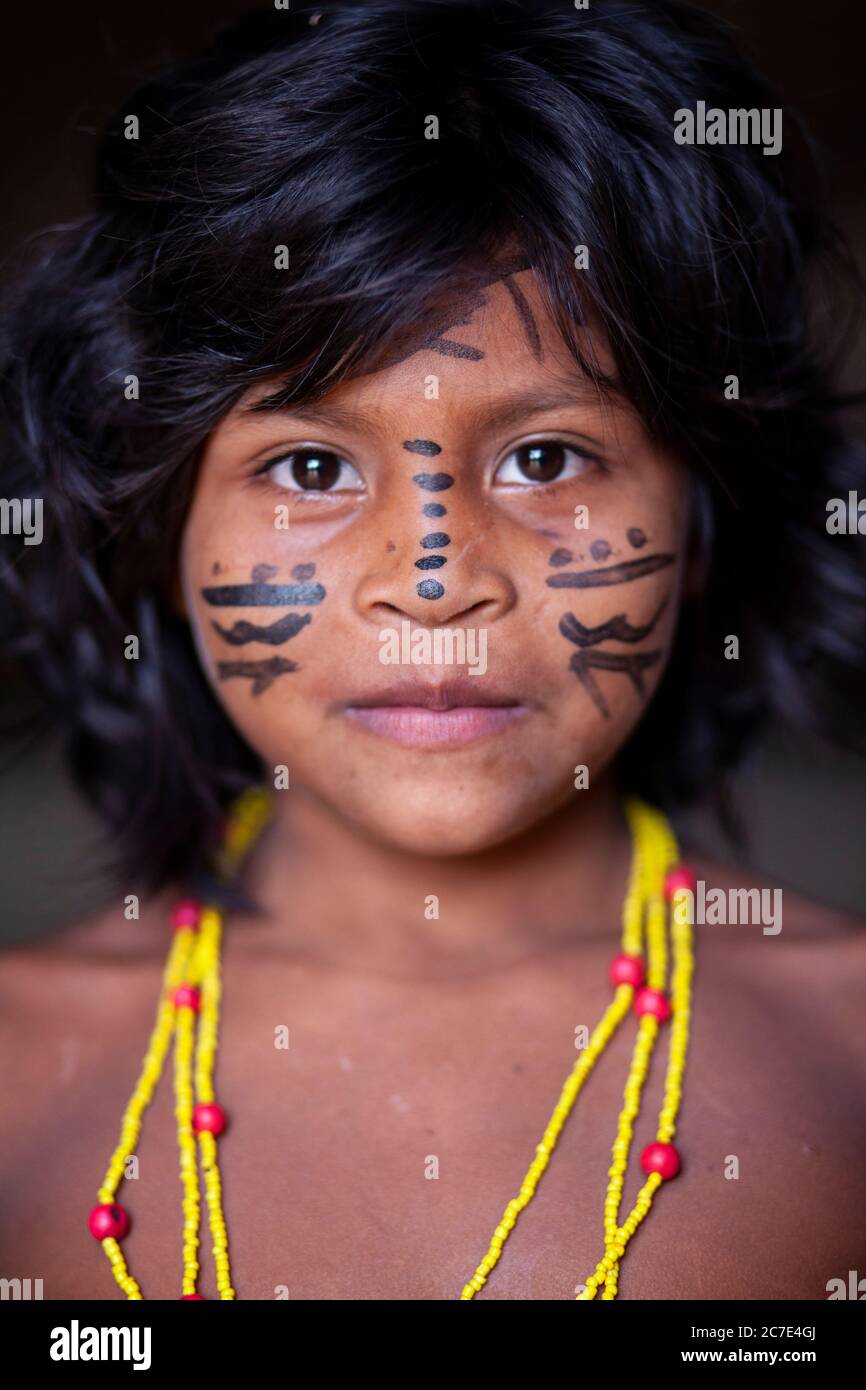 Ritratto di un bambino indigeno amazzonico con tradizionale vernice per il viso e collana con perline, che celebra la vibrante cultura delle tribù indigene del Brasile. Foto Stock