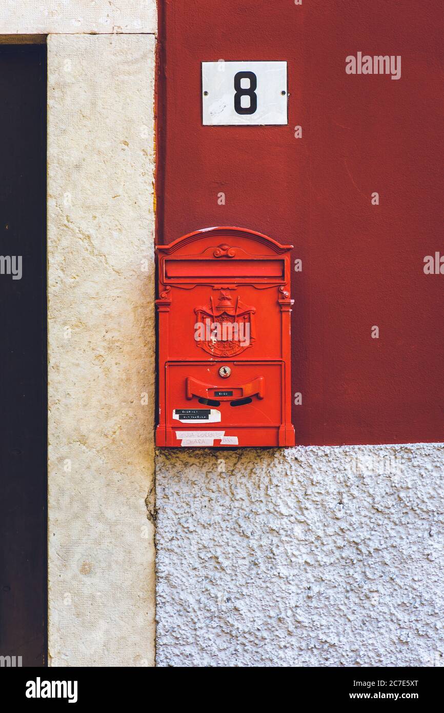 Primo piano verticale di una cassetta postale rossa con la città cresta incisa su di esso e una targa di casa sopra Foto Stock