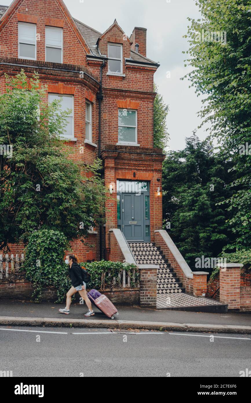 Londra, UK - 02 luglio 2020: Casa inglese tradizionale a Hampstead, una zona ricca di Londra favorita da artisti e figure dei media, donna con suitc Foto Stock