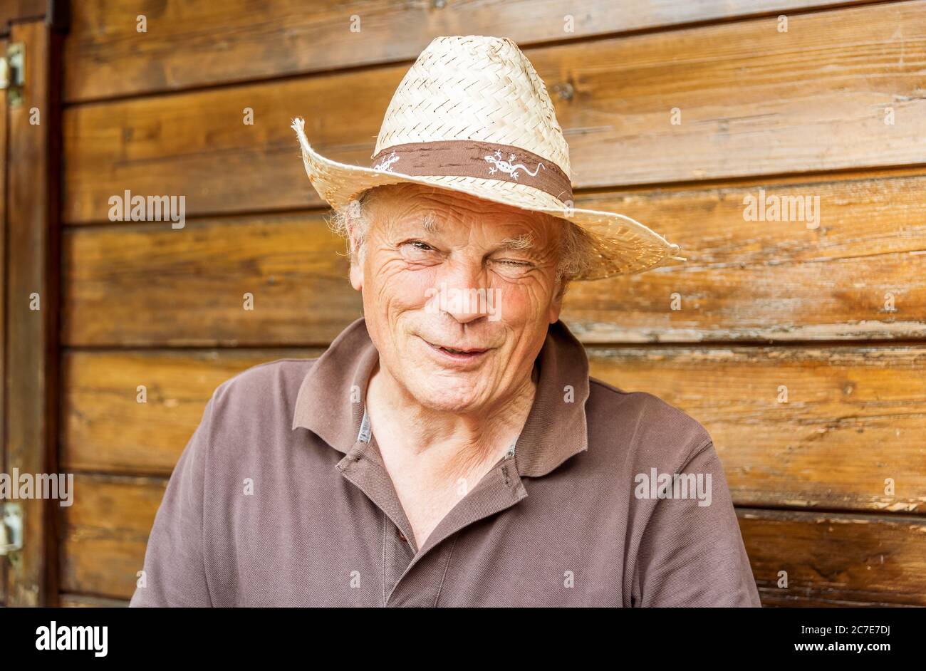 Ritratto di un uomo anziano sorridente che indossa un cappello nel suo orto in primavera. Foto Stock
