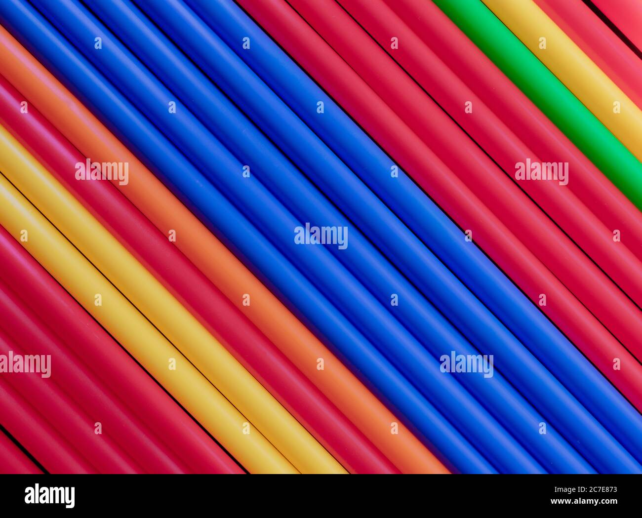 Tubi colorati in plastica si stagliano su fondo diagonale centrale blu Foto Stock