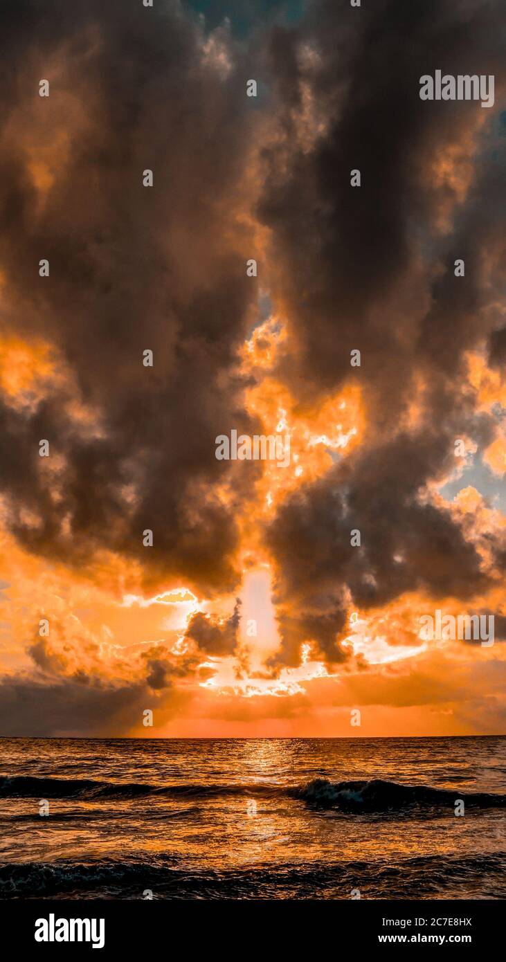 Scatto verticale di un mare bello con il riflesso di le nuvole mozzafiato assomiglia a un fuoco Foto Stock