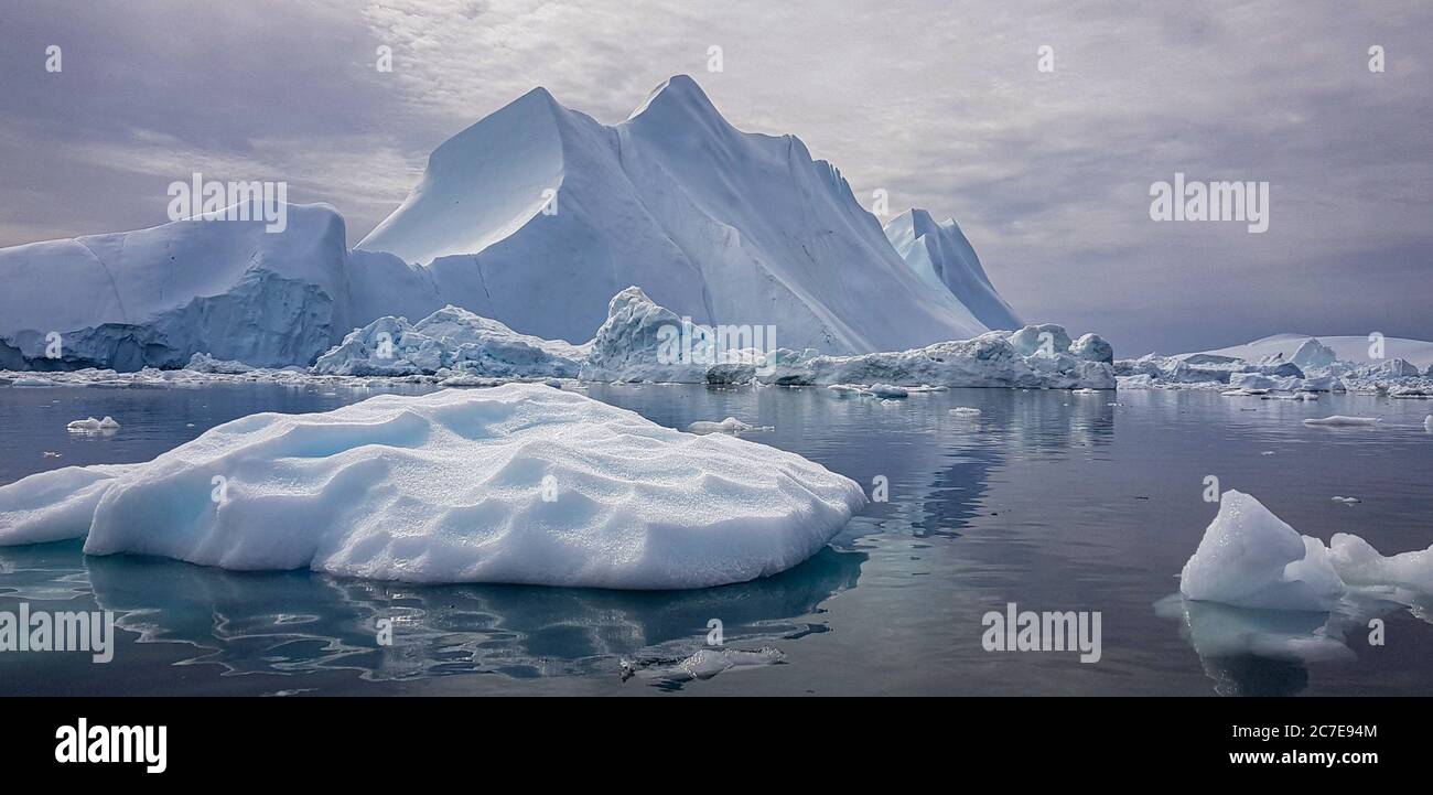 Iceberg gigante la dimensione di una montagna in Groenlandia circondata da piccoli iceberg Foto Stock