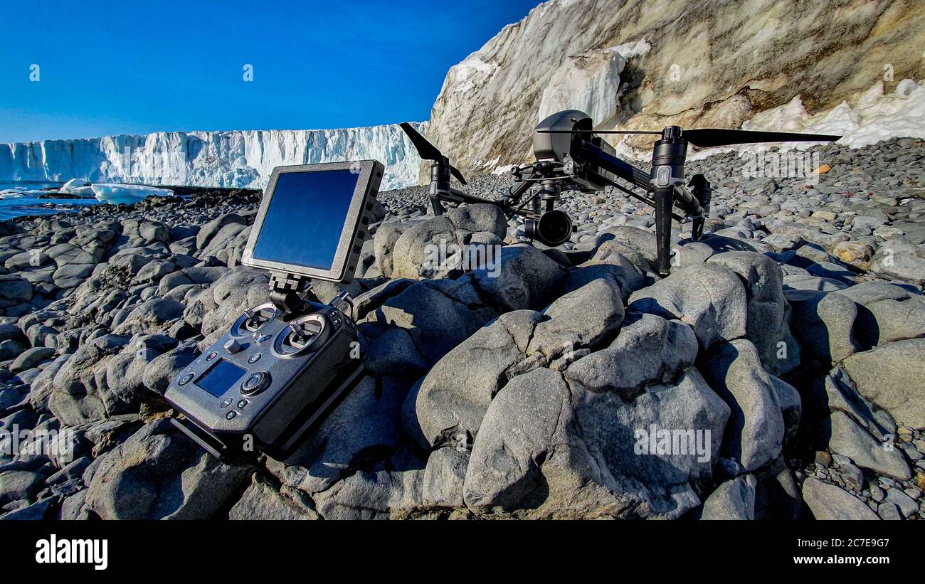 Drone e controller seduti su rocce con ghiacciaio sullo sfondo Foto Stock