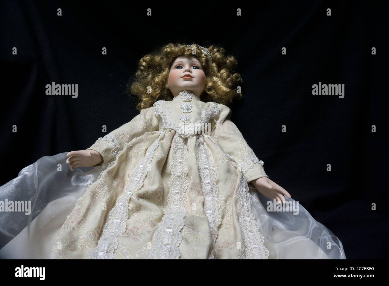 Vecchia bambola infestata e spaventosa che galleggia su uno sfondo nero. Foto Stock