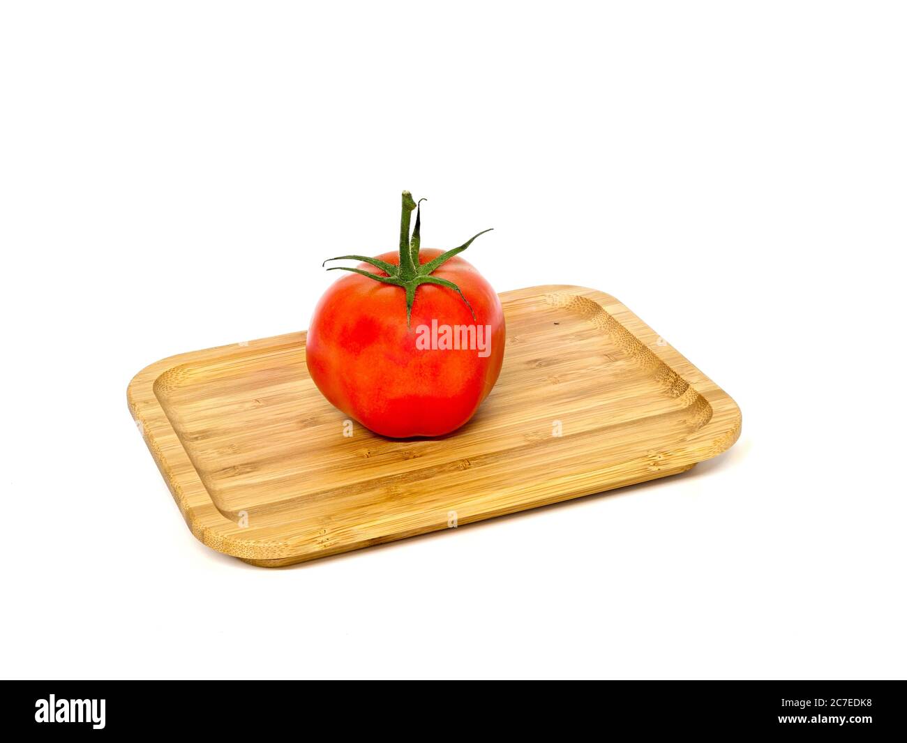 Pomodori, pomodoro a bush con gambo, grande, su una tavola di legno di fronte ad uno sfondo bianco. Foto Stock