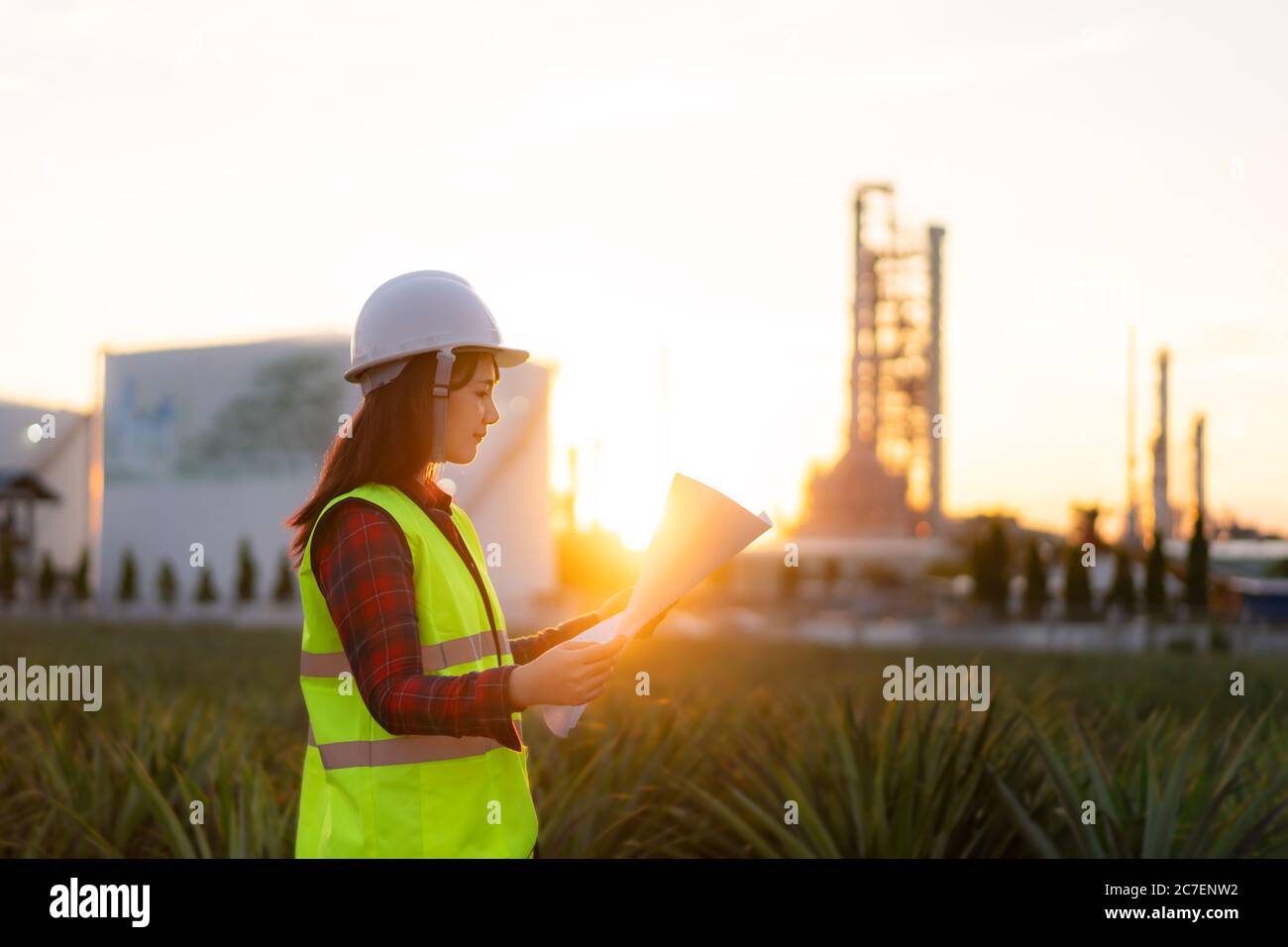 Donna asiatica ingegnere lavoro controllo presso l'industria energetica centrale produzione petrolio raffineria. Impianto di controllo tecnico con progetto. Foto Stock