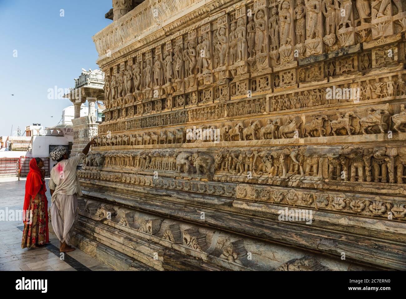 Una coppia che osserva un'opera d'arte scolpita sulle pareti del Tempio Jagdish a Udaipur, Rajasthan Foto Stock