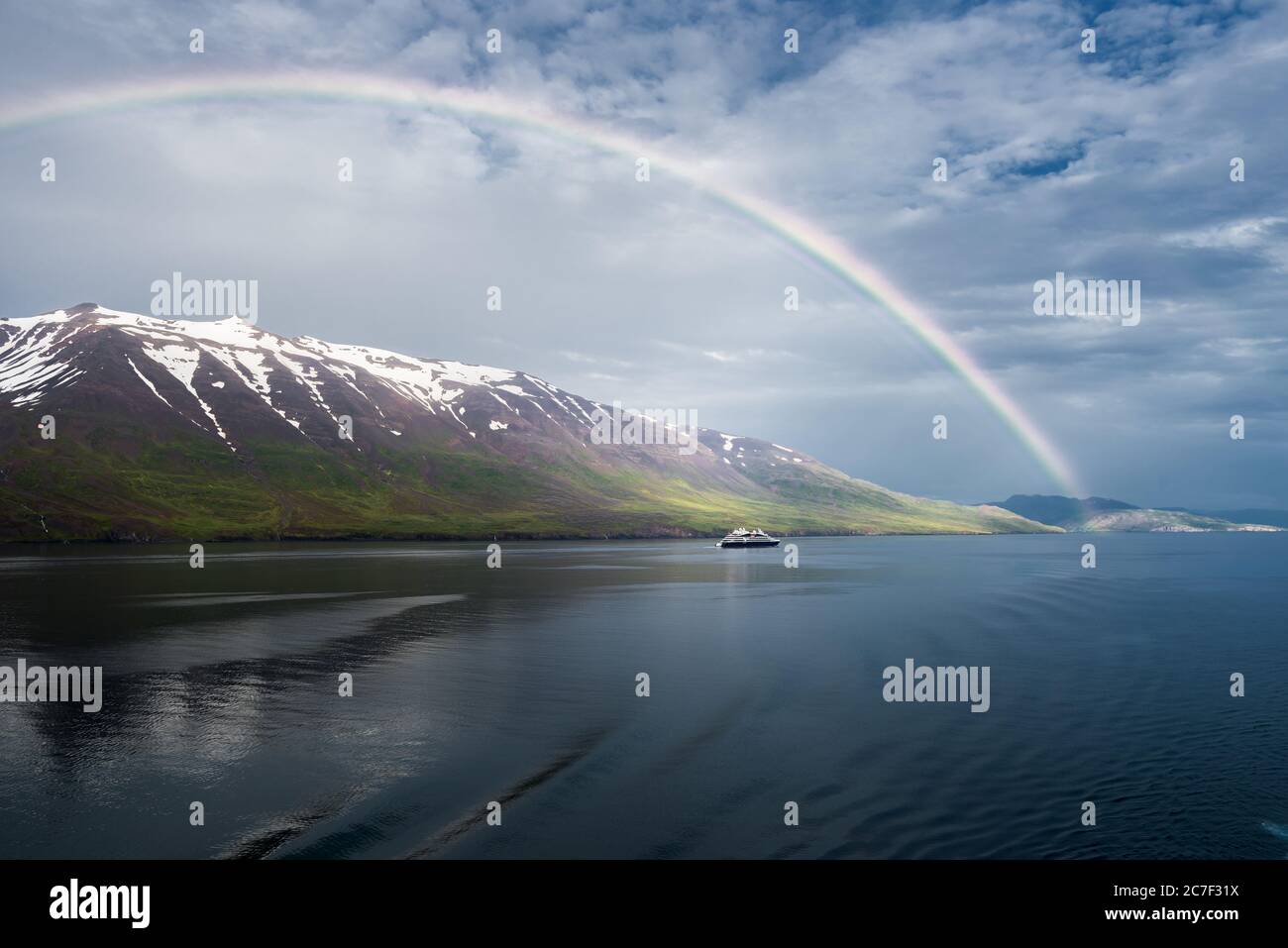 L'arcobaleno sul mare vicino alle montagne innevate e. una nave isolata Foto Stock