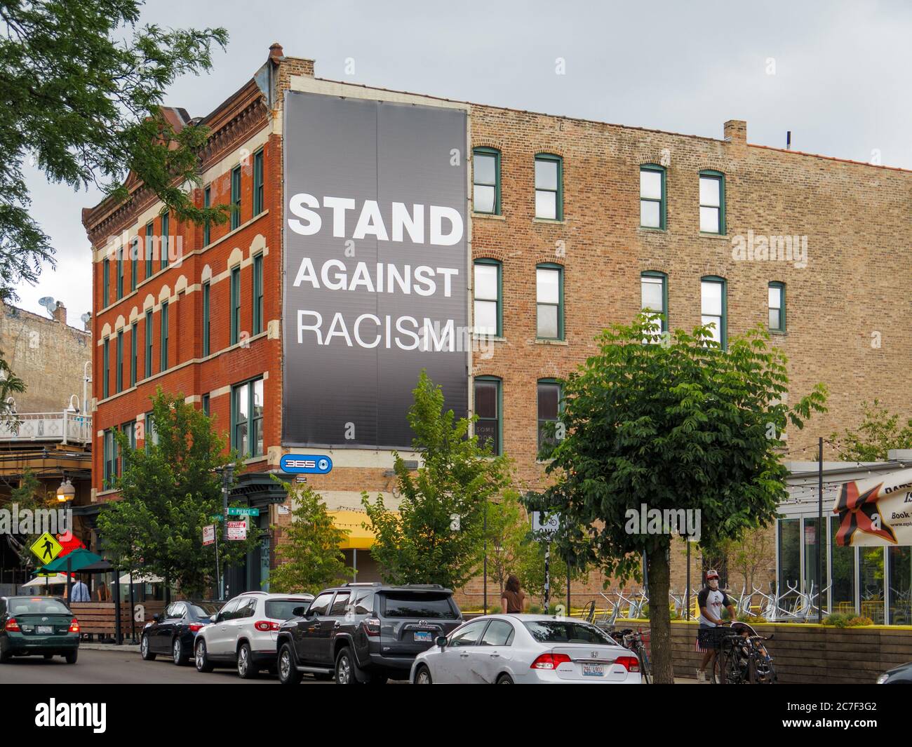 Vista a nord su Damen Avenue, quartiere di Wicker Park di Chicago. Opporsi alla bandiera del razzismo sull'edificio. Foto Stock