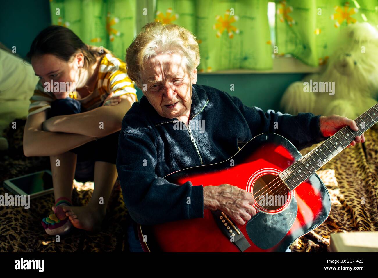 Una vecchia donna anziana suona la chitarra per sua nipote. Foto Stock