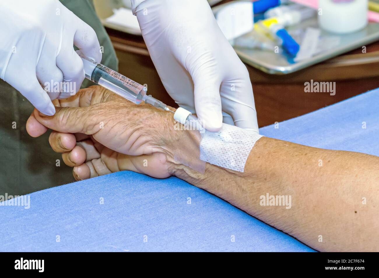 Siringa a pressione del medico nel tappo eparina mano del paziente Foto Stock