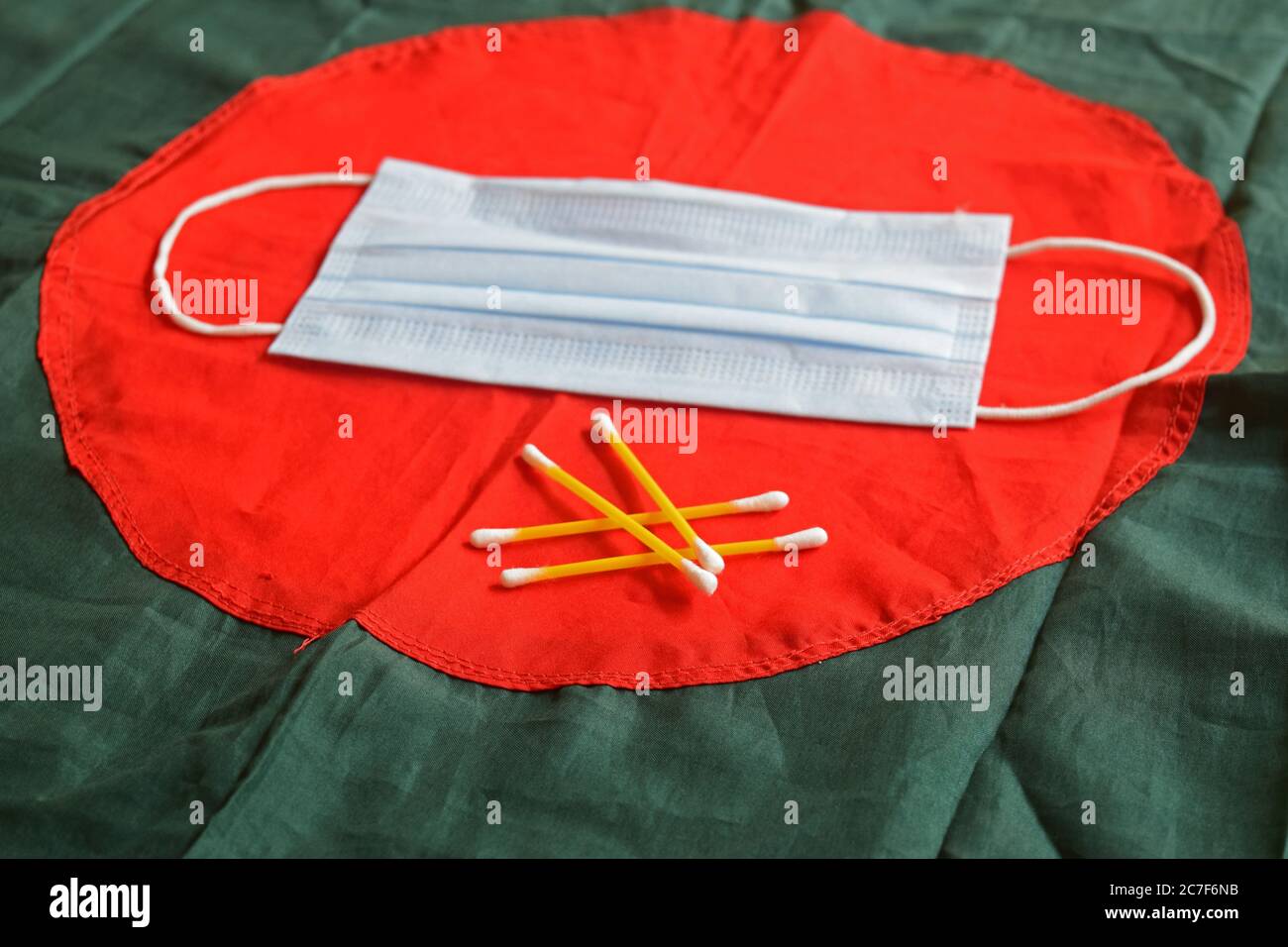 Maschera sulla bandiera del Bangladesh e alcuni bastoncini di cotone Foto Stock