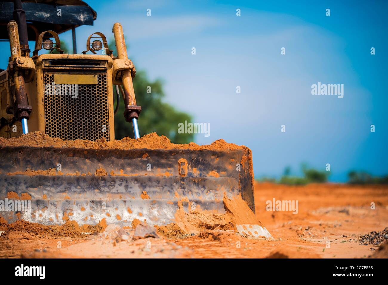Bulldozer giallo sulla sabbia con un cielo blu luminoso sullo sfondo Foto Stock