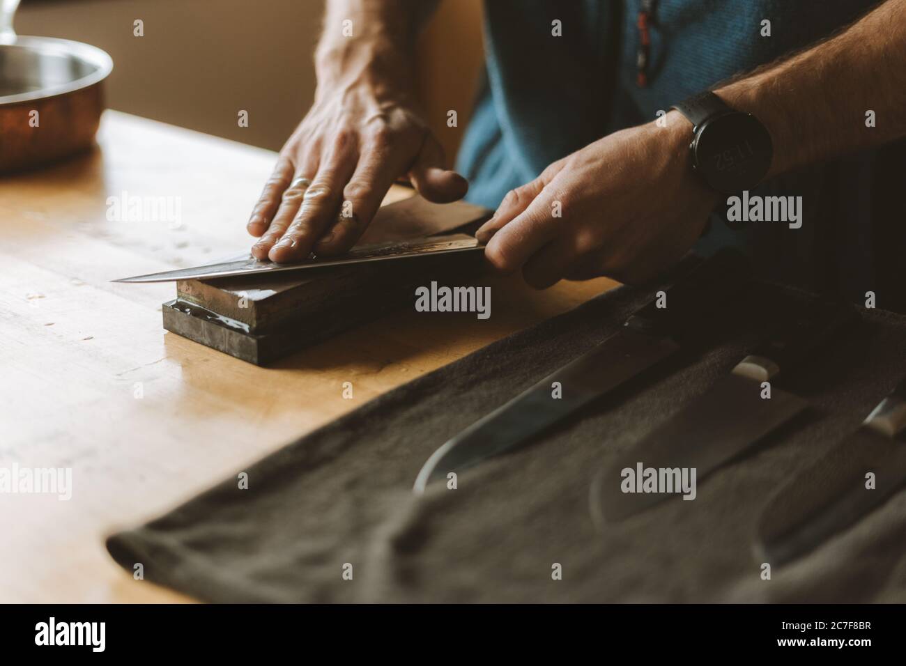Affilare i coltelli con una pietra da cetone in cucina Foto Stock