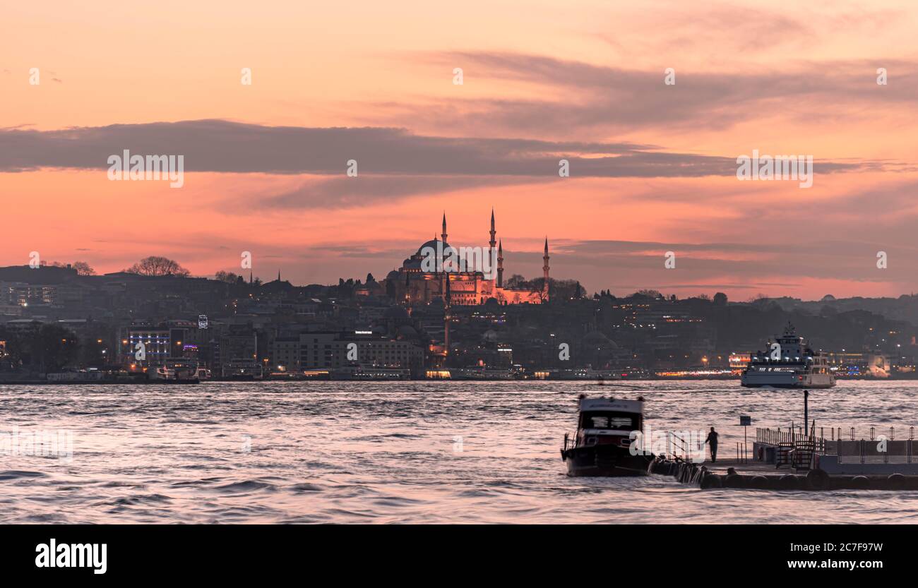 Barca sul Bosforo, la sagoma della moschea Yeni Cami e Beyazit Cami, al tramonto, Istanbul, Turchia Foto Stock