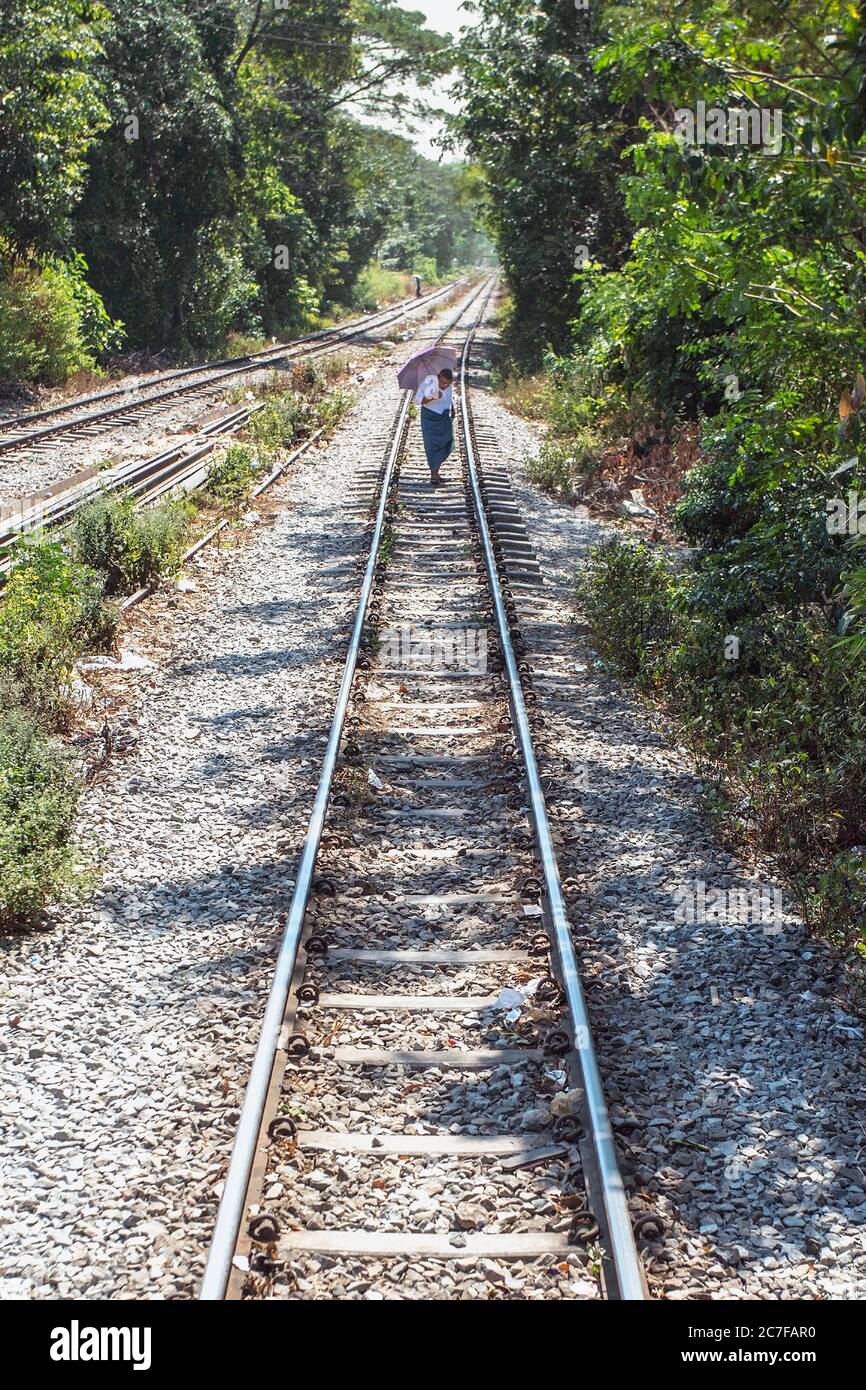Una persona che cammina lungo i binari del treno della ferrovia circolare Yangon in Myanmar Foto Stock