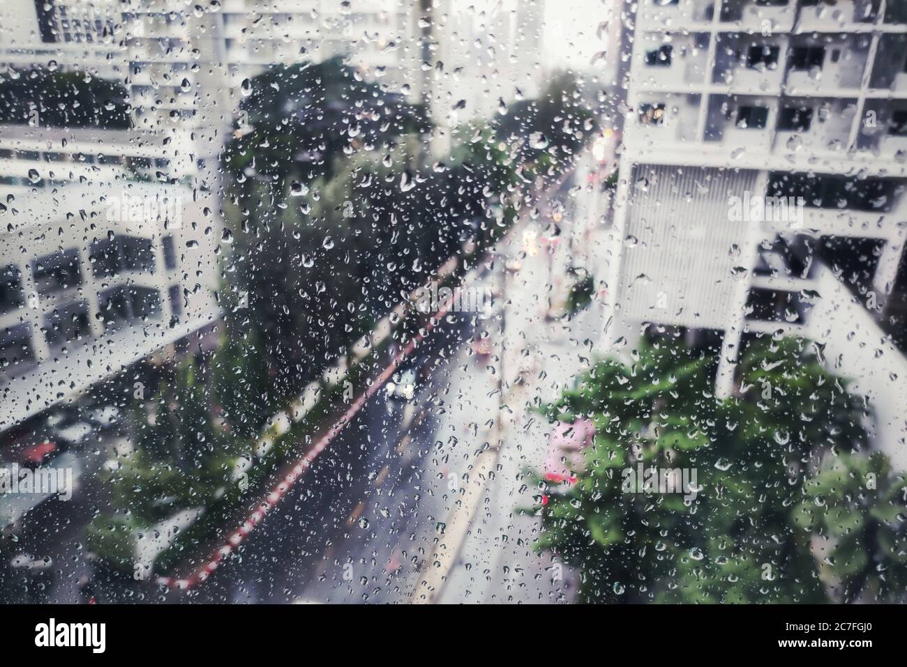 piovendo sulla strada, vista aerea. goccia d'acqua catturata sulla finestra di vetro dell'appartamento. guardando giù sulla strada durante la tempesta. strada bagnata e guida attenta co Foto Stock