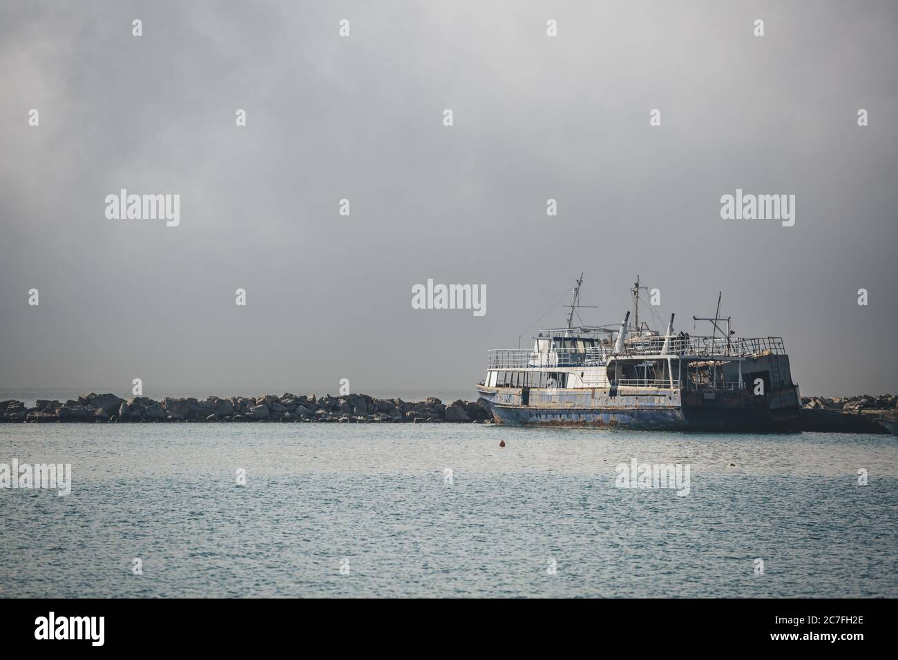 Vecchia nave abbandonata quasi il naufragio ormeggio sulla superficie del Mar Ionio nel porto dell'isola greca di Zante in mattinata nebbiosa Foto Stock
