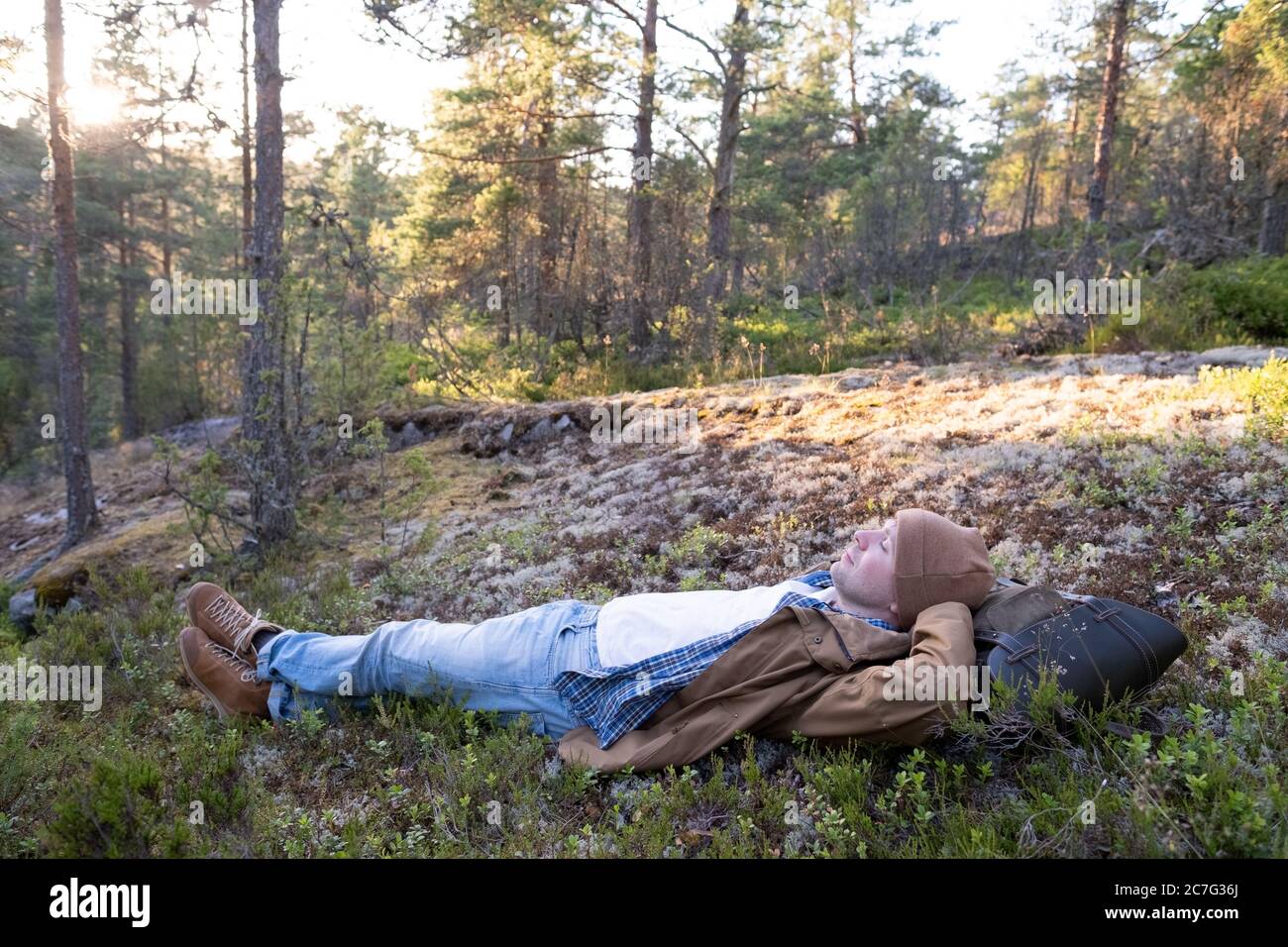 L'uomo giace sull'erba, riposandosi nel mezzo della foresta rilassante Foto Stock