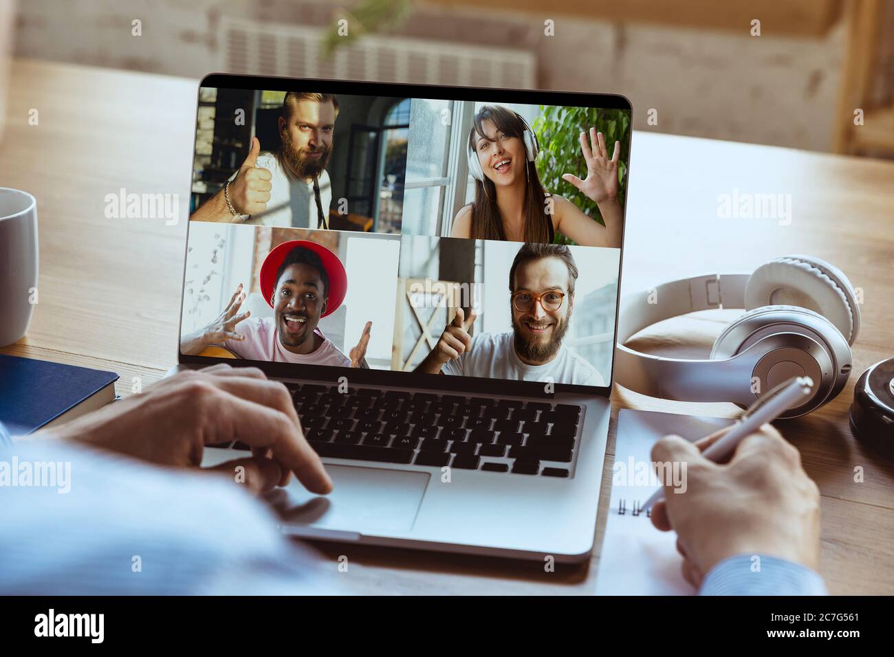 Riunione remota. Uomo che lavora da casa durante la quarantena di coronavirus o COVID-19, concetto di ufficio remoto. Giovane capo, manager davanti al laptop durante una conferenza online con colleghi e team. Foto Stock